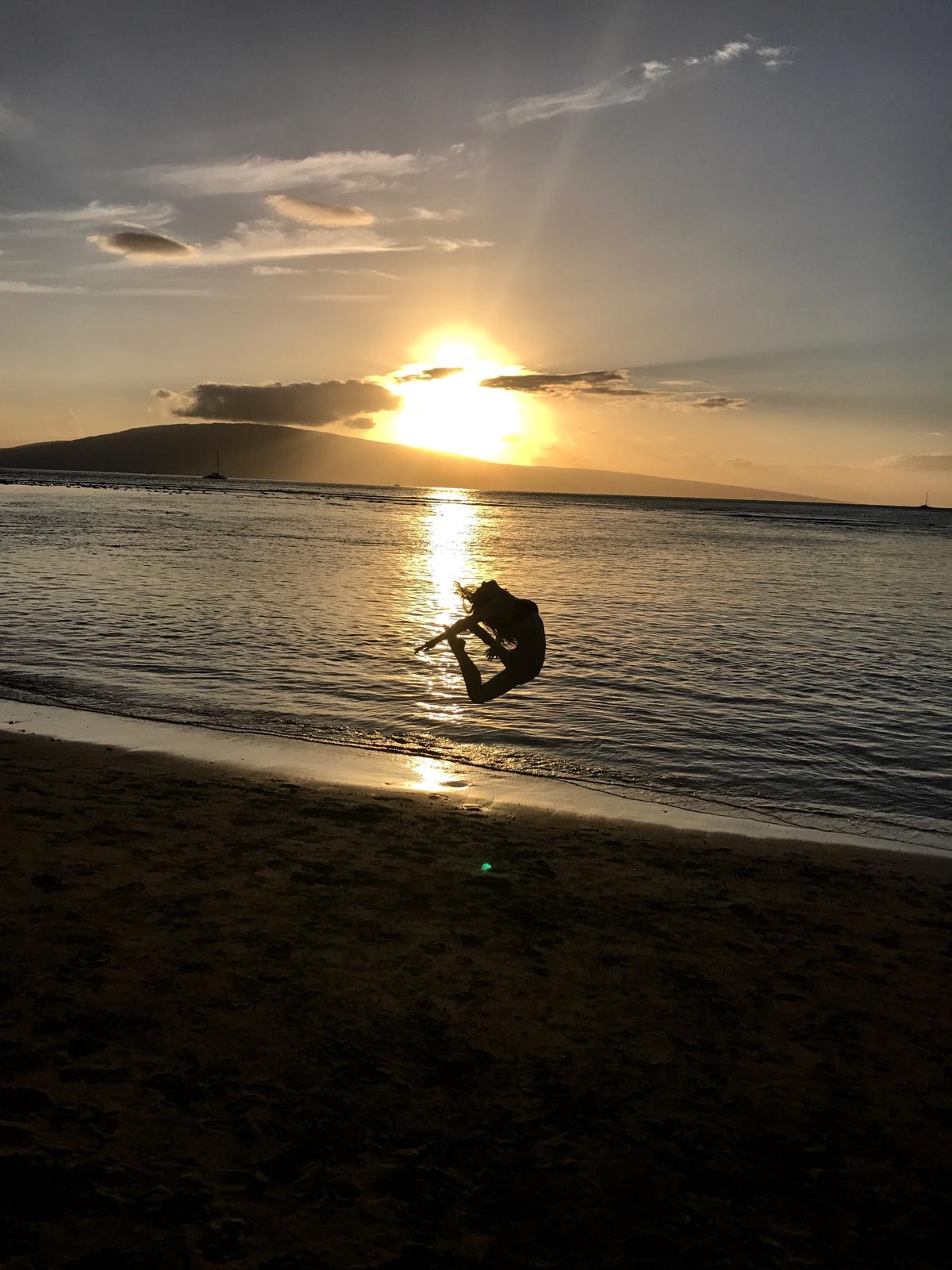 Hannah mid-leap on the shoreline at sunset
